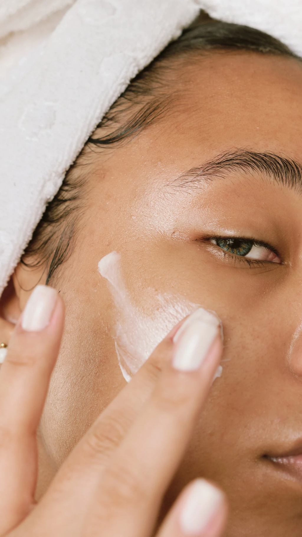 Close-up of a beautiful woman applying Freelifer Skincare Clear Skin moisturiser, smiling with glowing skin.