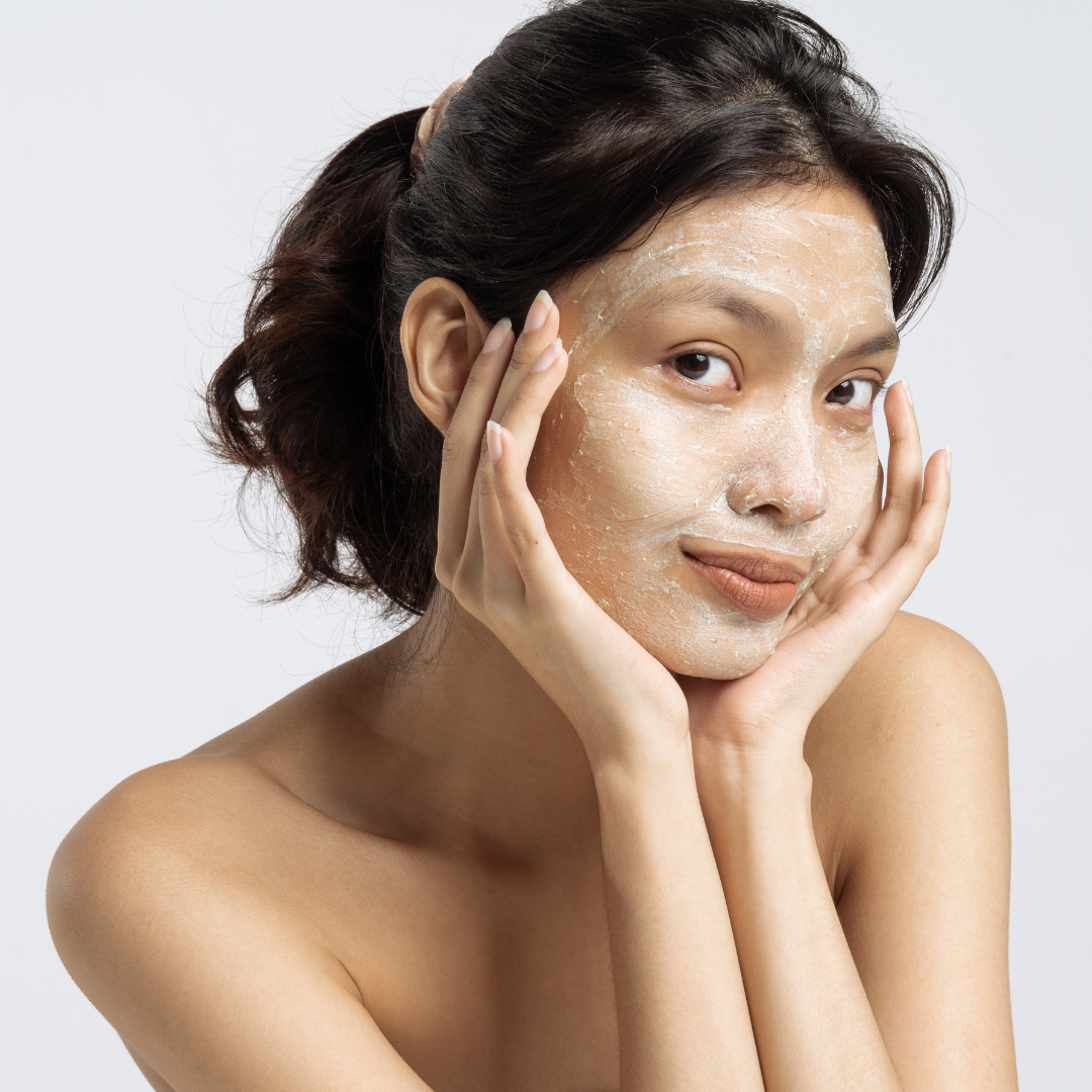 Close-up of a beautiful woman applying Freelifer Skincare Clear Skin Exfoliant, smiling with glowing skin.